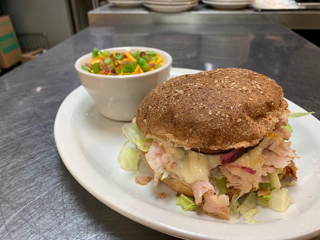 Turkey Trotter Sandwich · Grilled sliced smoked turkey with Monterey Jack cheese, mayo, lettuce, tomatoes, and red onion on a toasted wheat bun.