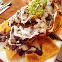Nachos con Steak · Corn tortillas with streak strips, beans, lettuce, melted cheese topped off with sour cream ...