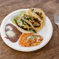 Taco Combo · Includes onions, cilantro, cheese, sour cream and avocado sauce. Served with rice and beans.
