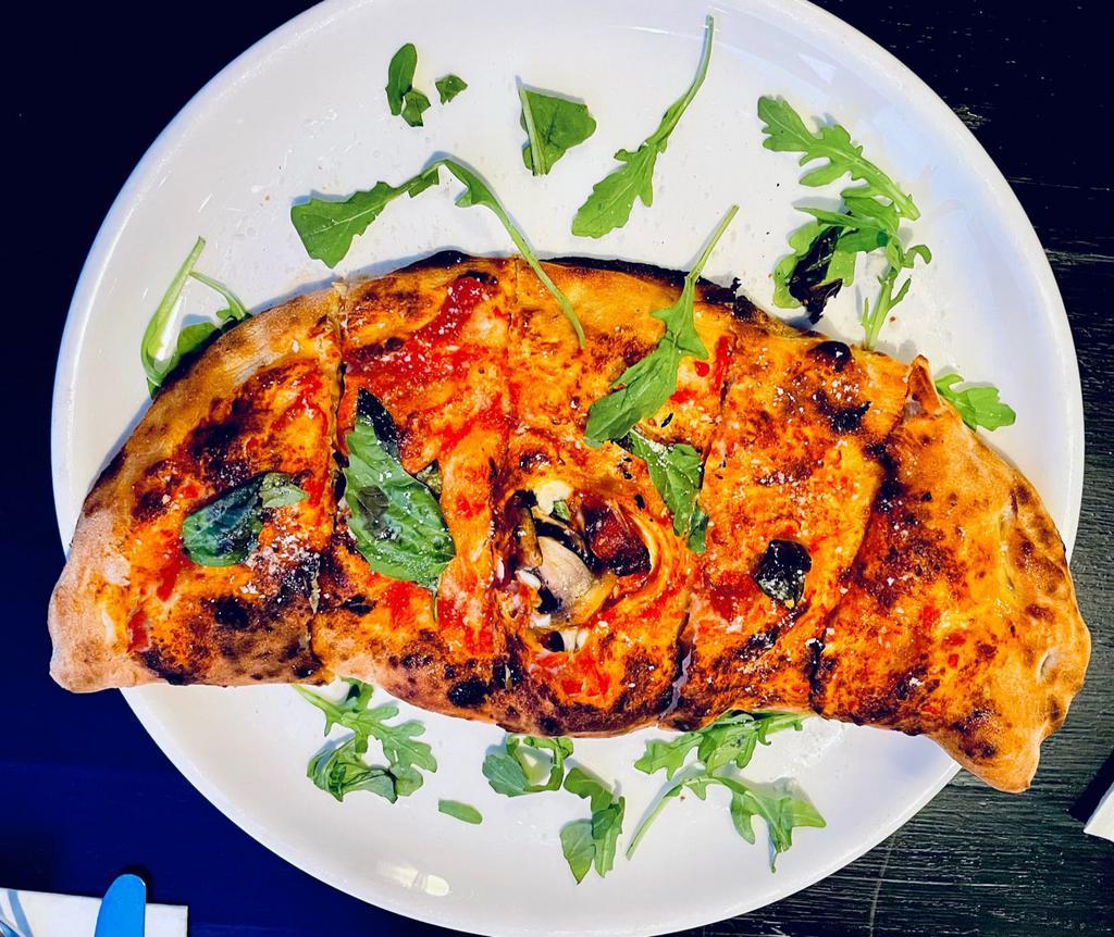 Calzone Liola · Homemade Mozzarella, ricotta, prosciutto crudo, mushrooms, basil, cherry tomatoes with a sprinkle of EVO, shaved parmigiano, and touch of arugula.