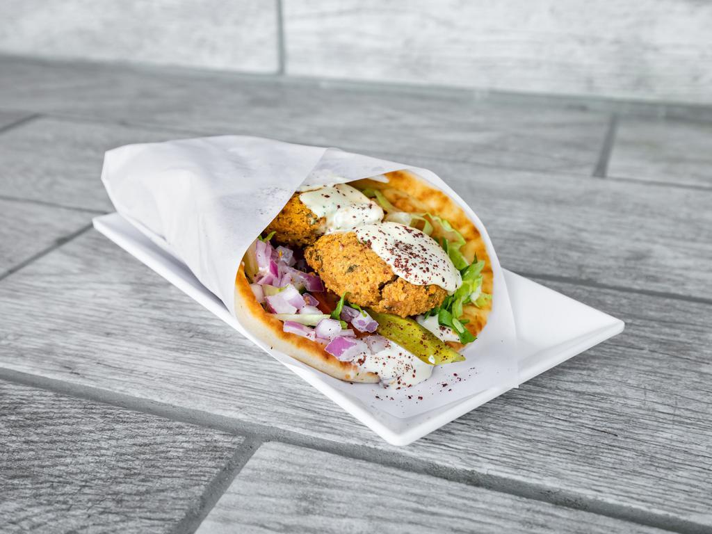 The Falafel Sandwich · Our signature blend of falafels deep fried into a golden crust with the perfect fluff on the inside, wrapped in a toasty pita with lettuce, tomatoes, onions, pickles and a drizzle of tahini sauce. Vegan. Vegetarian.