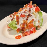 Wedge Salad · Iceberg lettuce wedge topped with bacon, tomatoes, bleu cheese crumbles, and bleu cheese dre...