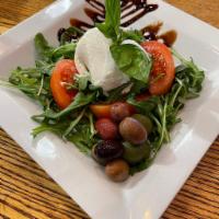 Caprese Salad · Burrata, sliced tomato, olives and basil over arugula served with balsamic glaze