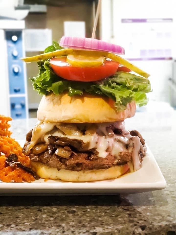 Mushroom Swiss Burger · Fresh beef patty smothered in garlic sauteed mushrooms, Swiss cheese and housemade bordelaise sauce. Served with lettuce, tomato, onions & pickle chips.