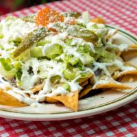 Nachos · Chips with refríes beans, melted mozzarella, choice of meat iceberg diced tomatoes, grated C...