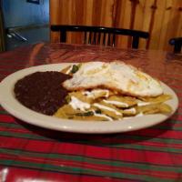 Chilaquiles · Crispy tortilla chips cooked in choice of sauce with a drizzle of sour cream and grated Ques...