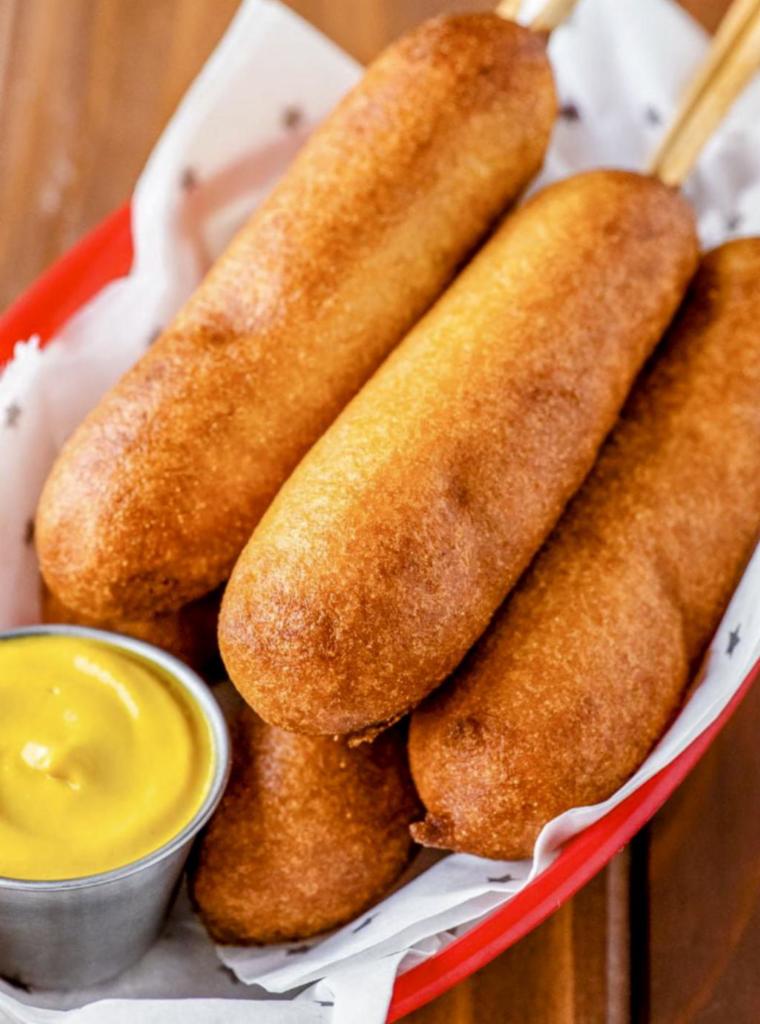 Fair Ground Corn Dogs · Crunchy yet moist, savory with a hint of sweet, these are the corn dogs you remember from being a kid. Introduce a true American classic to your young ones, or just remember what it was like to be a kid again. You get two delicious corn dogs, AND a scoop of our award winning Mac and Cheese for just $12. Add two more corn dogs for just $7.  Treat yourselves!