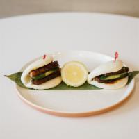 A6. Kakuni Bun · 2 pieces. Braised pork belly sandwiched in fluffy steamed bun served with cucumber, scallion...