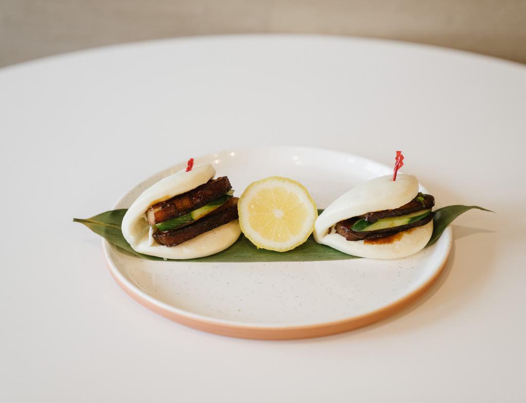 A6. Kakuni Bun · 2 pieces. Braised pork belly sandwiched in fluffy steamed bun served with cucumber, scallion and chef’s special sauce.