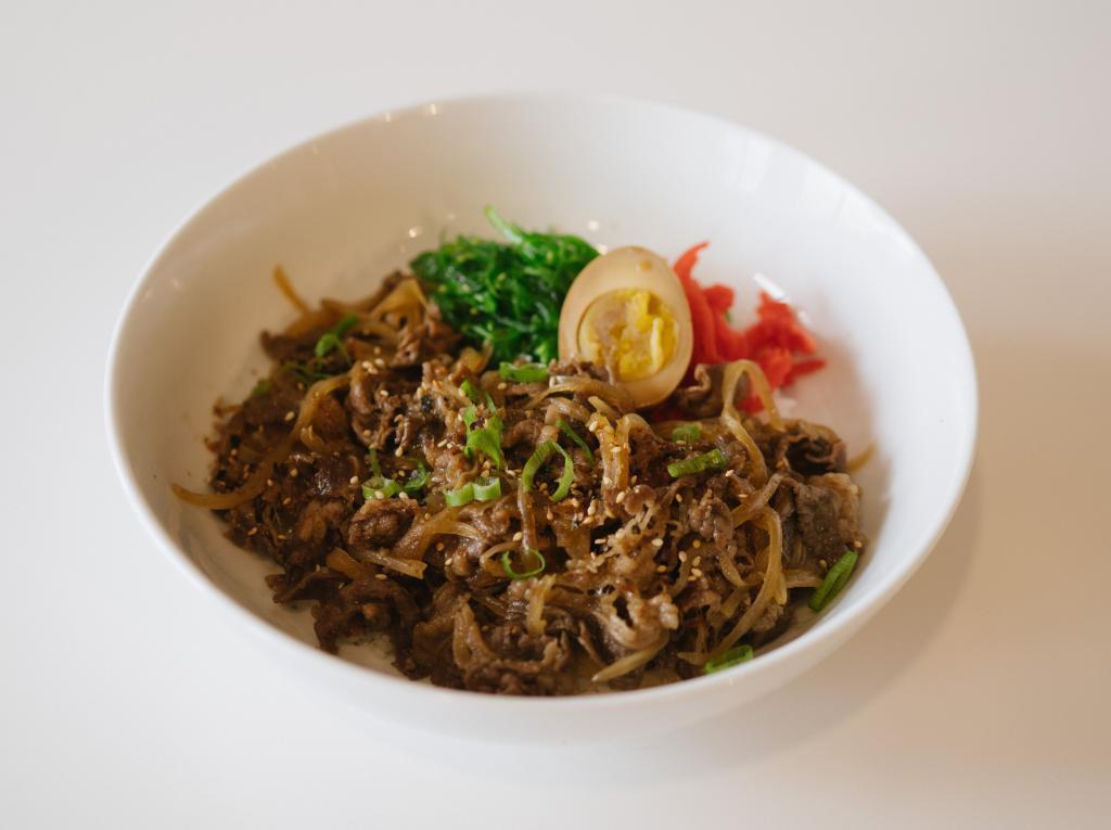 D5. Gyudon · Marinated and thinly sliced beef brisket cooked with onions, picked ginger, seaweed salad, soy marinated egg, scallions and sesame seeds over rice.