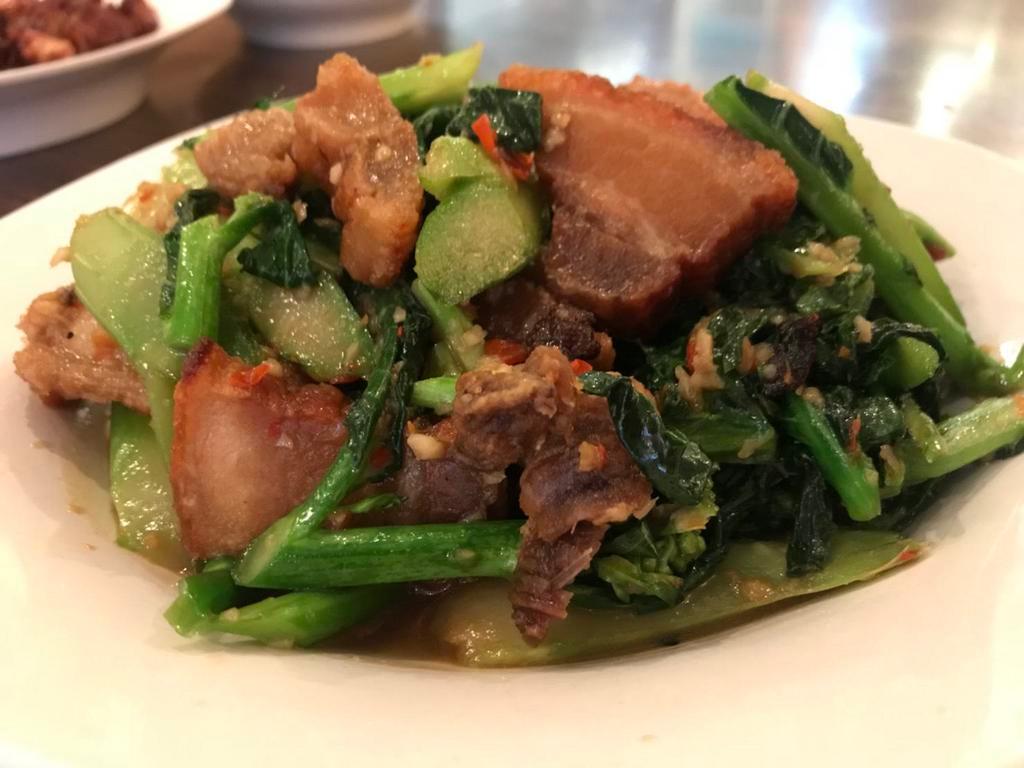 Signature Crispy Pork Belly with Green Kana · Homemade crispy pork belly stir fried with fresh garlic, Thai chili and green Chinese broccoli in light brown sauce.