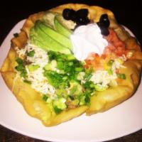 Grilled Chicken Taco Salad · Crisp flour shell filled with refried beans, lettuce and grilled chicken. Topped with shredd...