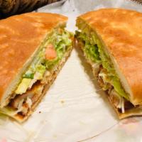 Torta Milanesa de Pollo · Breaded chicken, served w/ mayo, guacamole, beans, lettuce, tomatoes, onions and cheese.