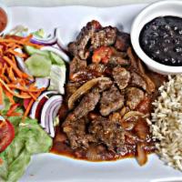 Bistec Encebollado · Grilled skirt steak topped with sauteed onions, served with rice, beans and salad.