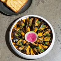 Mejillones en curry · Mussels curried in spicy cilantro coconut milk, served with corn bread.