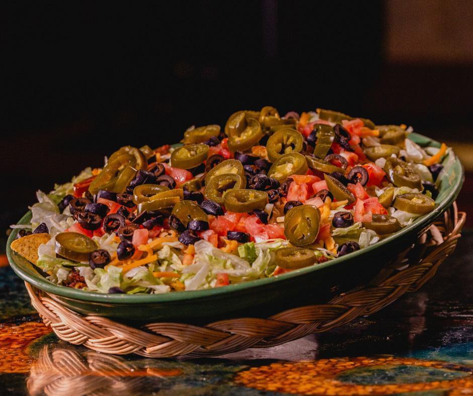 Super Nachos · For you, nacho lovers large plate of corn chips layered with seasoned ground beef, refried beans and melted cheese, garnished with peppers, lettuce, tomato and black olives - our own invention. Large enough to share. Add extras for an additional charge.