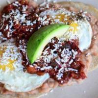 HUEVOS RANCHEROS · Two house corn tortillas topped with refried beans, ranchero sauce, two fried eggs, fresh av...