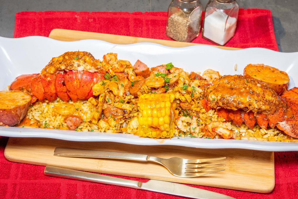 Stuffed Lobster Tails w/Loaded Rice · 2 Seasoned grilled lobster tails stuffed with cajun fried rice and loaded with grilled shrimp, chicken, and sausage.  With 1 corn and 1 potato. 