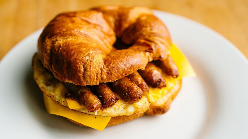Sausage, Egg, and Cheese Croissant · Flaky buttery croissant served with 2 fresh cracked eggs, choice of cheese and pork sausage links.