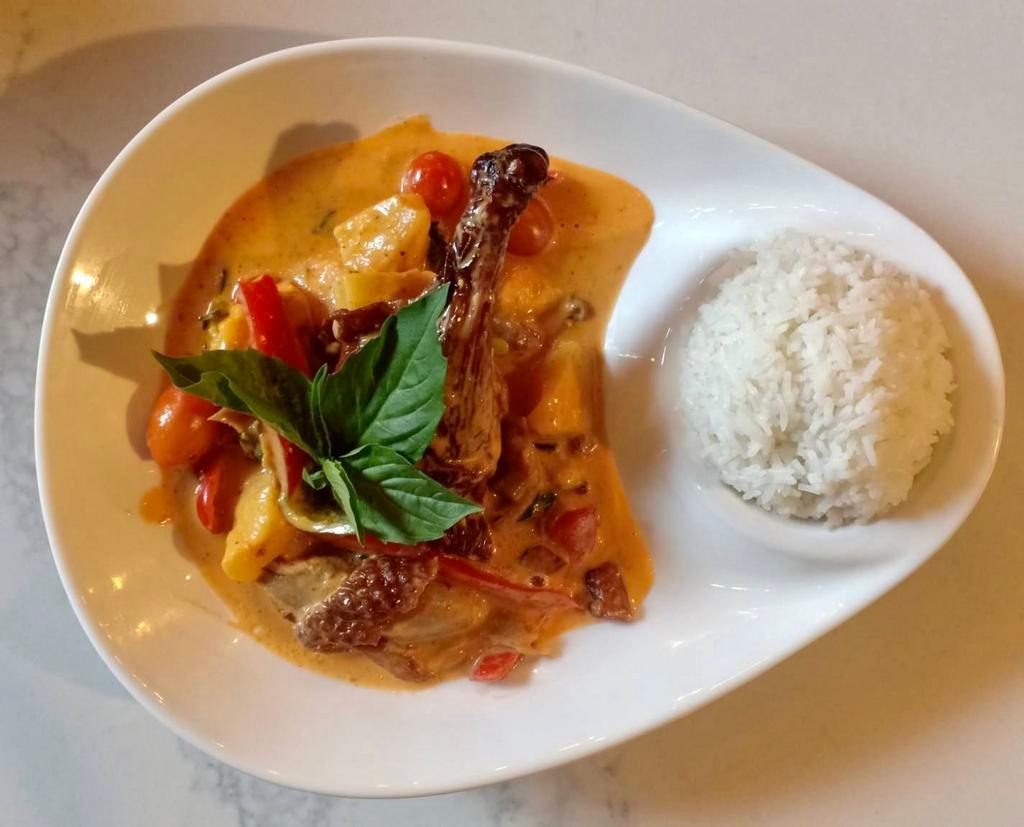 Duck Curry · Red curry with roasted duck, pineapples, tomatoes, bell peppers, and basil leaves.