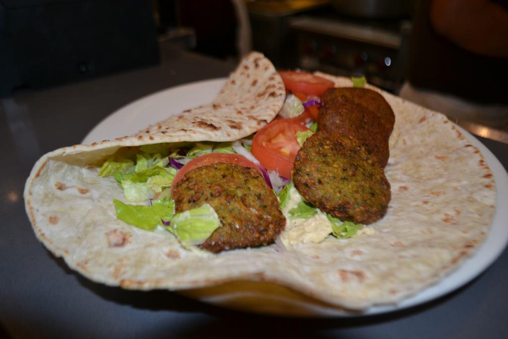 Falafel Wrap · A mixture of chickpeas, celery, parsley and green onions tossed in spices and fried. Served with lettuce, onion and sliced tomatoes with red spicy, tahini, and white cacik sauce.