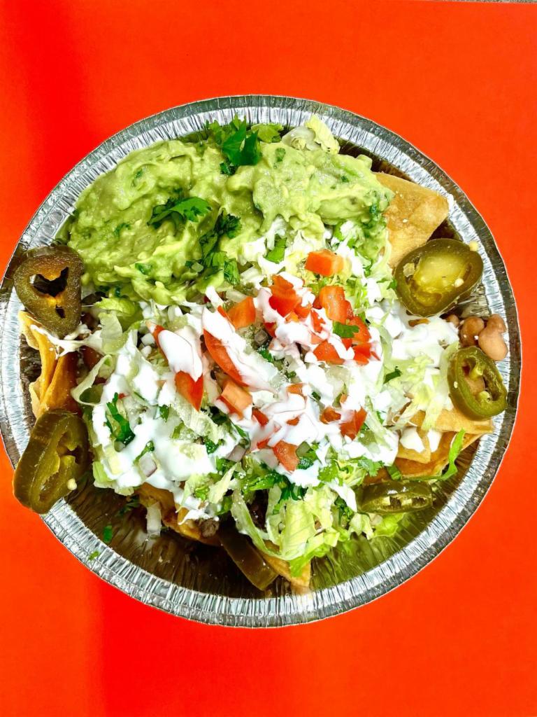 Nachos · Homemade chips with beans, quesillo, guacamole, jalapenos, sour cream, cotija cheese, lettuce, tomatoes, and onions.