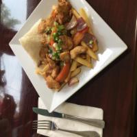 Lomo Saltado De Pollo · Chicken Sautéed with Onions, Tomatoes, and Soy Sauce Over a Bed of French Fries, Served With...