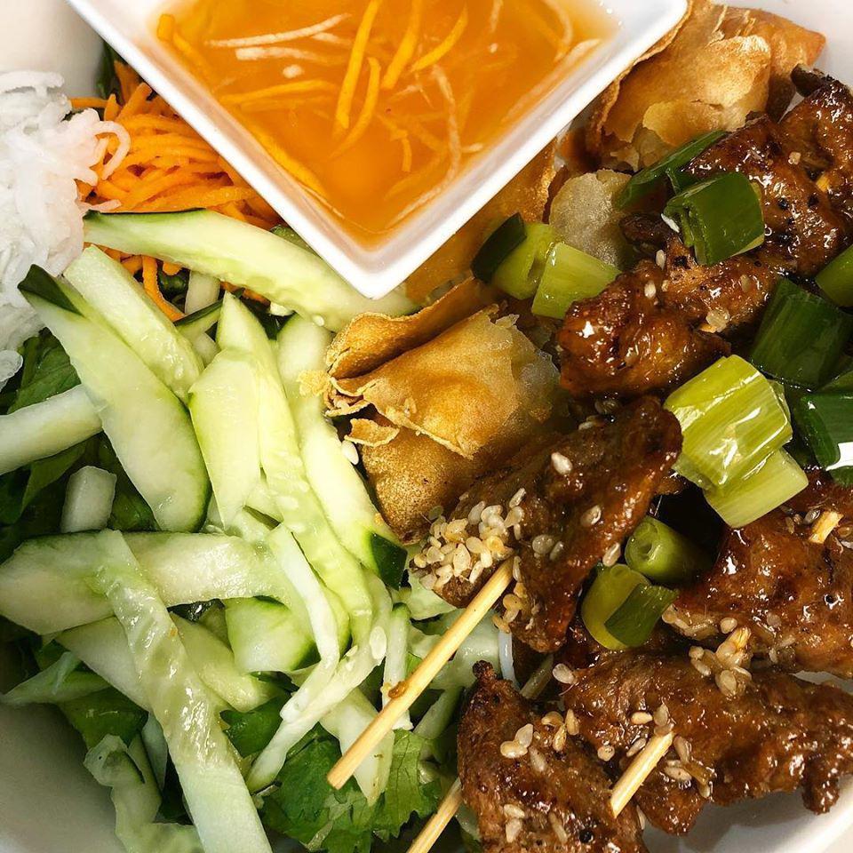 Vegan Non La Combo Grilled Bowl · Grilled lemongrass marinated 100% vegan beef skewers and a tofu roll. Vietnamese rice vermicelli noodles, topped with mixed greens, cracked peanuts, basil, green onions, and pickled vegetables. Served with a side of vegan fish sauce vinaigrette or soy sauce dressing.