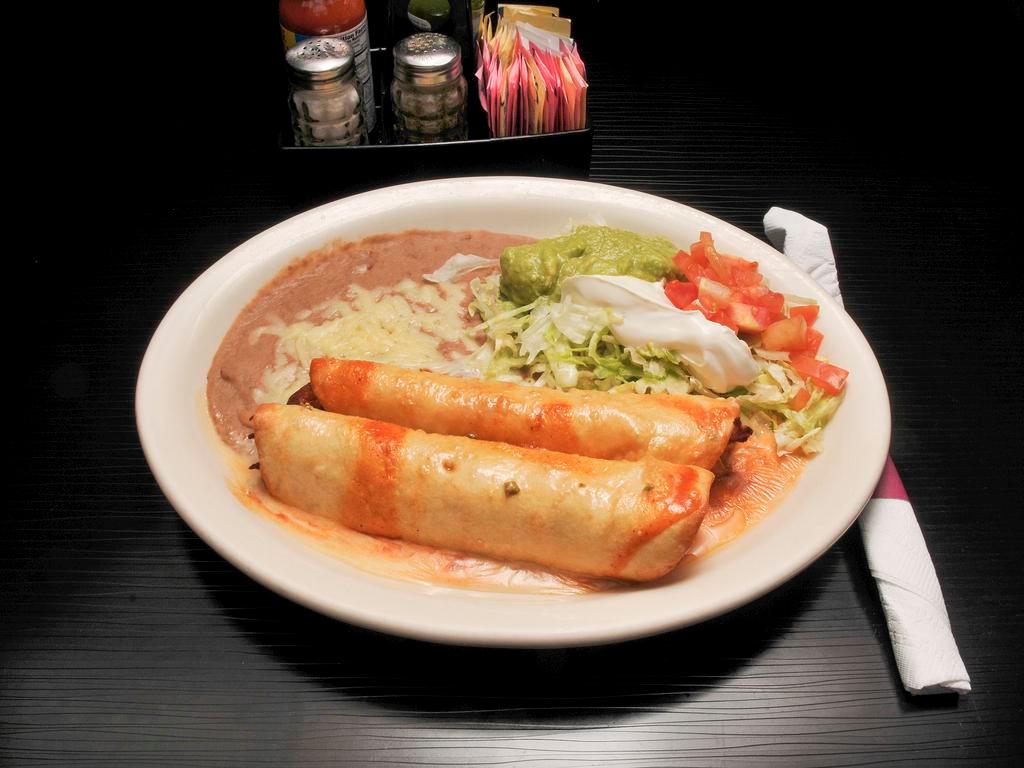 Soft Chimichangas · 2 flour tortillas filled with beef tips or chicken and beans. Topped with lettuce, tomatoes, sour cream, cheese dip and guacamole, with enchilada sauce.
