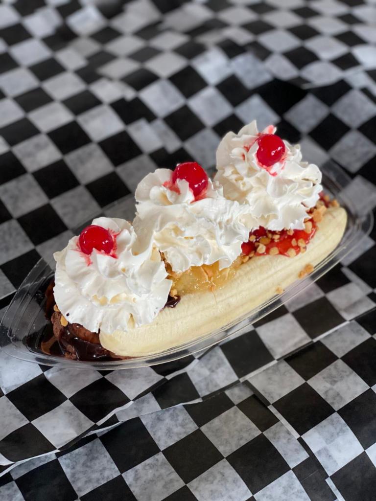 Banana Split Sundae · Our banana split is made with one scoop of vanilla ice cream topped with pineapple, chocolate ice cream topped with chocolate sauce and strawberry ice cream topped with strawberry topping. We then add one banana and top the ice cream with whipped cream and cherry.