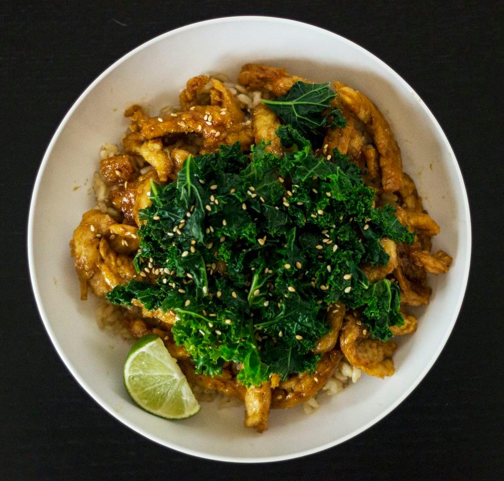 Sriracha Soy Bowl · Vegan, gluten-free. Pan-fried soy curls with house-made pineapple Sriracha sauce and onions, topped with steamed kale and sesame seeds. Served with brown rice. Add sauce, add-ons, toppings for an additional charge.