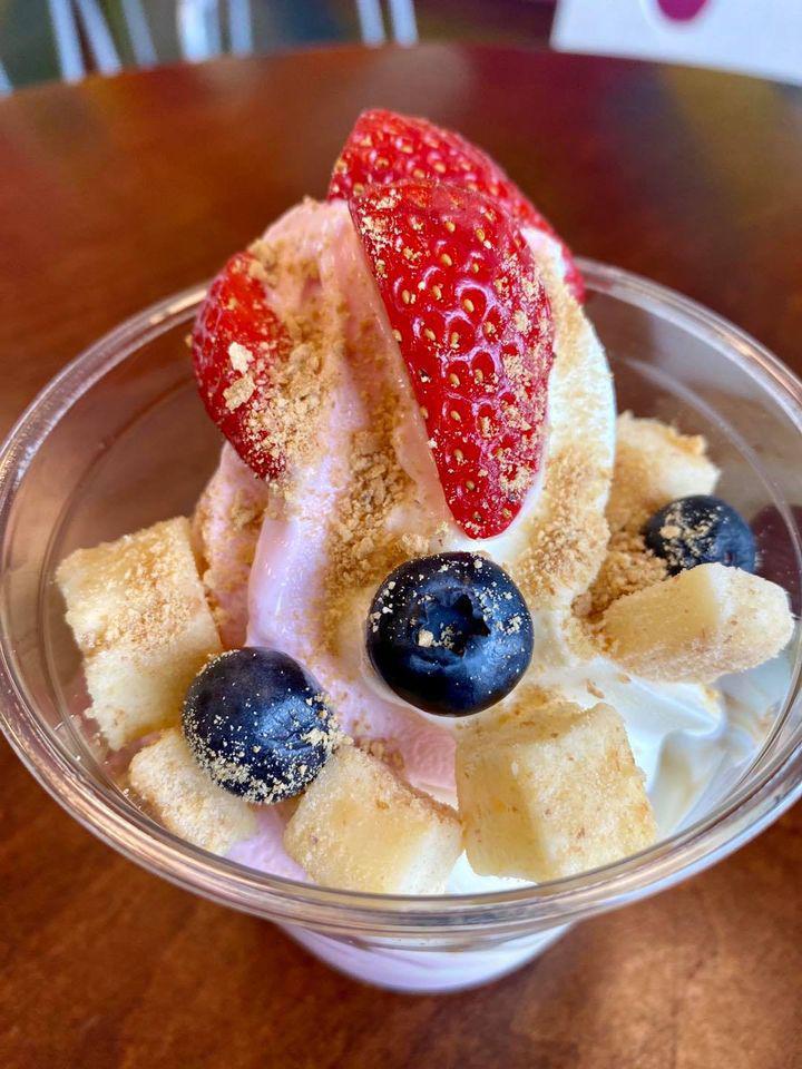 Strawberry Cheesecake · 9 oz. of swirled New York cheesecake and no-sugar added strawberry frozen yogurt topped with fresh strawberries, fresh blueberries, cheesecake bites, and a sprinkle of crushed graham crackers. We top it with a swirl of white chocolate syrup.
