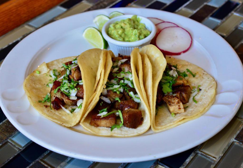 Carnitas Taco · Three soft corn tortillas filled with your choice of protein topped with cilantro and onion and guacamole on the side.