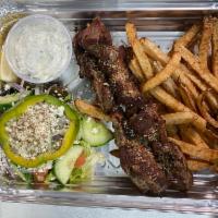 Pork souvlaki platter · Two skewers of pork cubes on grill seasoned with Greek herbs 