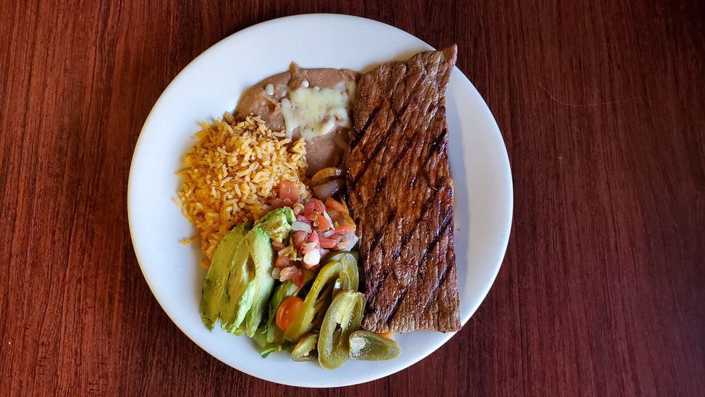 Carne Asada · Flavorful and juicy grilled steak. Served with grilled onions, rice, beans, lettuce, pico de gallo, avocado, jalapenos and tortillas.