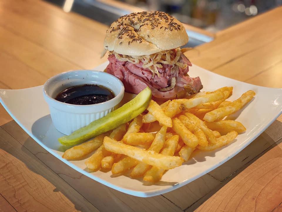 Beef on Weck Sandwich · Shaved prime rib on a Kimmelweck roll with crispy onions served with au jus and horseradish cream.