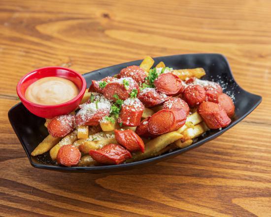 Salchipapas · French fries tossed in garlic and Parmesan cheese topped with cilantro and pink sauce on the side