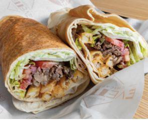 Steak Shawarma Wrap · Spiced shredded ribeye steak, Lebanese pita, tahini sauce, shredded lettuce, sumac onion, tomato, pickles, fries (in the wrap), and cucumber labneh.