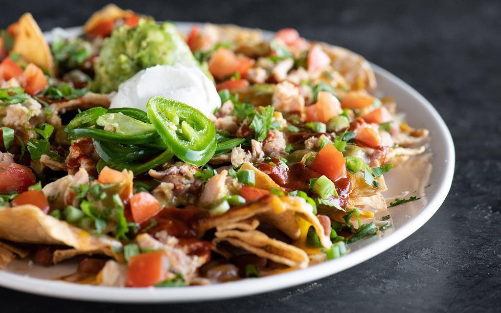 Chicken Nachos · Pinto beans, cheddar, monterey jack, tomato, cilantro, red & green sauce, onions, crushed avocado, sour cream, house pickled jalapeños.