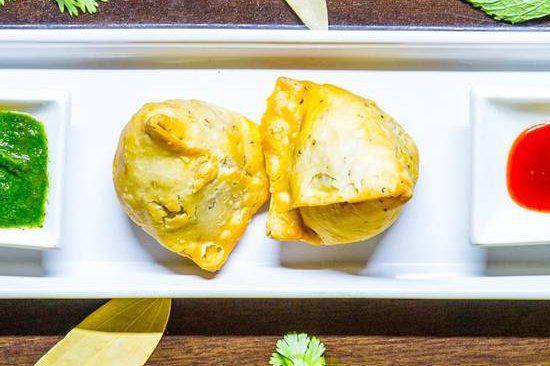 Samosas (2 pcs) · Crispy fried dumplings filled with spiced potatoes and peas served with chutney.