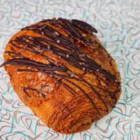 Chocolate Croissant · A flakey chocolate croissant filled with 64% dark chocolate sticks and topped with cacao nibs.