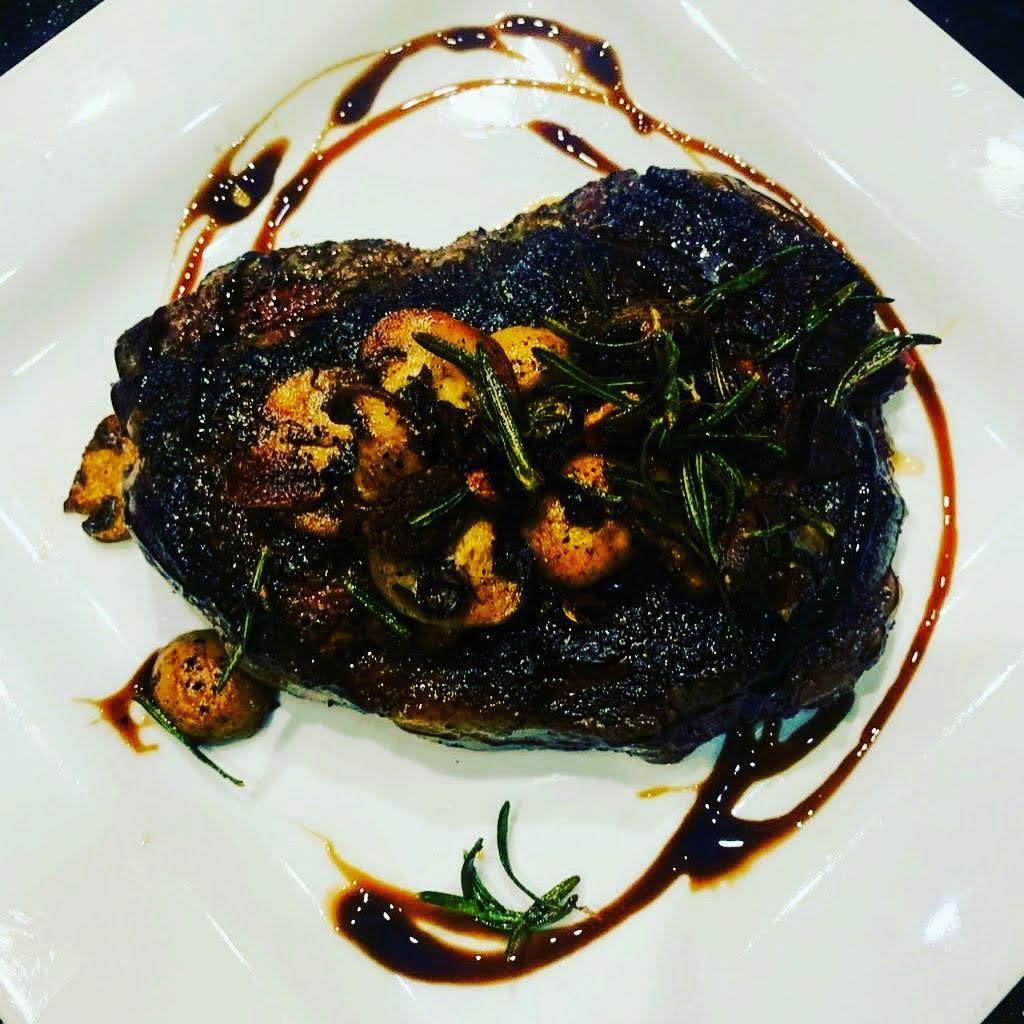 14OZ Cast Iron RIBEYE · On a bed of our Signature Mashed Potatoes topped with Garlic, Rosemary, Portabella Mushrooms and our Balsamic reduction sauce