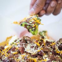 Carne Asada Nachos · Carne asada, nachos, guacamole, beans, sour cream, and cheese.