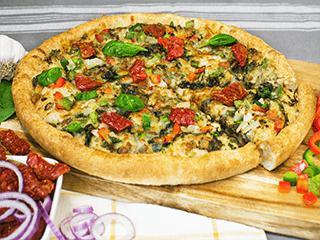 Pesto Veggie Pizza · Homemade garlic pesto sauce and loaded with sun-dried tomatoes, tender red and green peppers, fresh spinach leaves, onions, freshly chopped garlic, melty cheddar, and our signature gourmet cheese blend. Vegetarian.