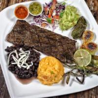 Carne Asada · A skirt steak accompanied by a side of charro beans and rice along with guacamole and a gril...