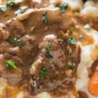 Pot Roast · Cooked in gravy with onions, carrots, and mushrooms served on a bed of mashed potatoes with ...