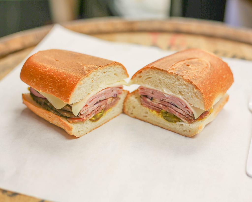 The Cuban Sandwich · Soft white roll, homemade pork shoulder, Black Forest ham, Swiss cheese, mayo, mustard, pickles, jalapenos and onions.