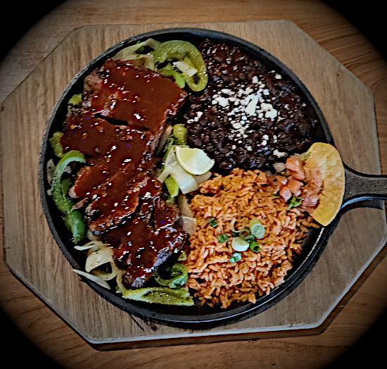 Chipotle BBQ Steak · You'll hear it coming. Served on a sizzling platter, accompanied with our specially spiced, sautéed onions and peppers. All fajitas are served with our famous Mexican rice and beans, sour cream, guacamole, lettuce, tomatoes, cheese, and warm flour or corn tortillas. Drizzled with spicy chipotle BBQ sauce.