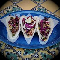 Original Fish Taco · Tortilla-encrusted fish, roasted corn salsa, shredded red cabbage, and chipotle aioli on sof...