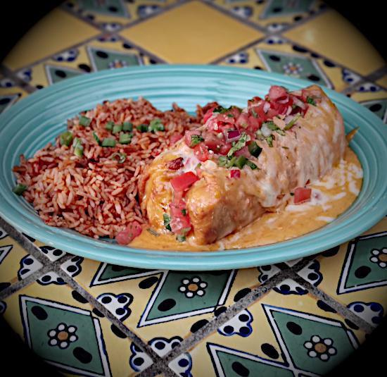 Steak Chimichanga · Seasoned chunks of sirloin and refried beans rolled in a flour tortilla, lightly fried, baked in queso, and topped with salsa fresca. Served with Mexican rice.